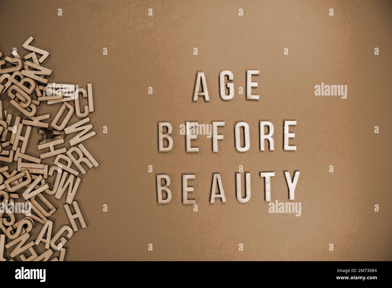 AGE BEFORE BEAUTY in wooden English words language capital letters spilling from a pile of