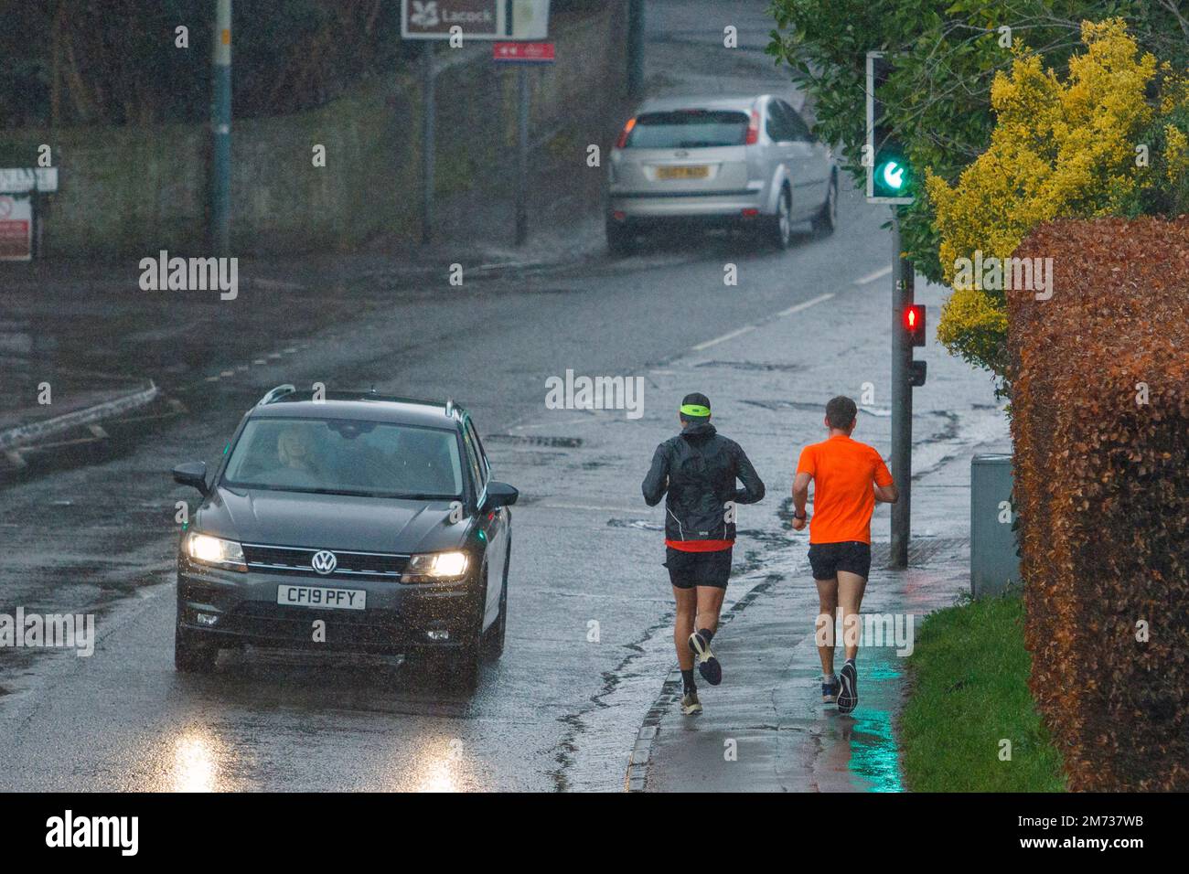 Chippenham, Wiltshire, UK. 7th January, 2023. Drivers and runners are pictured braving  heavy rain in Chippenham as showers make their way across Southern England. Credit: Lynchpics/Alamy Live News Stock Photo