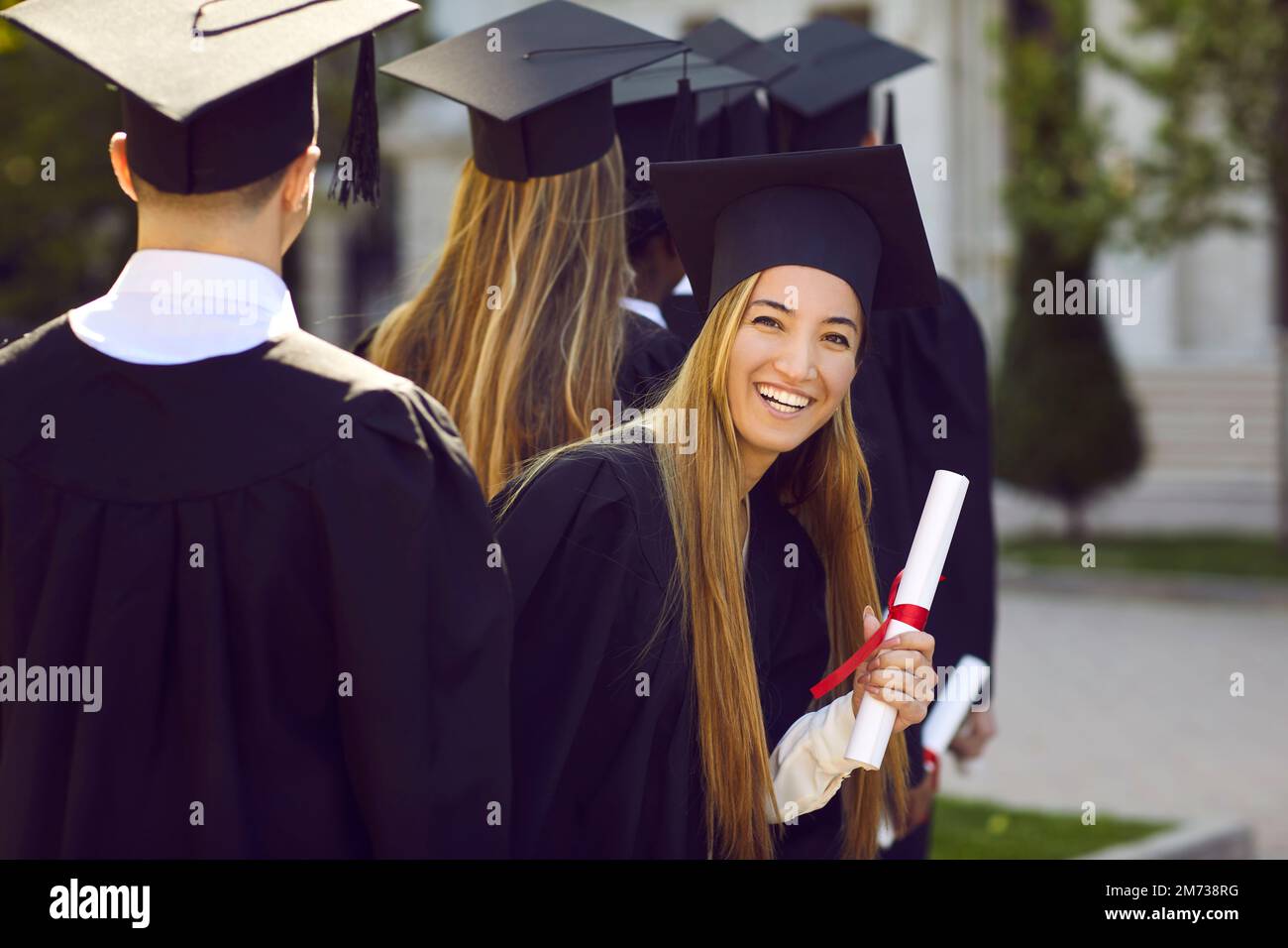 A young female graduate against the background of university graduates.  Stock Photo
