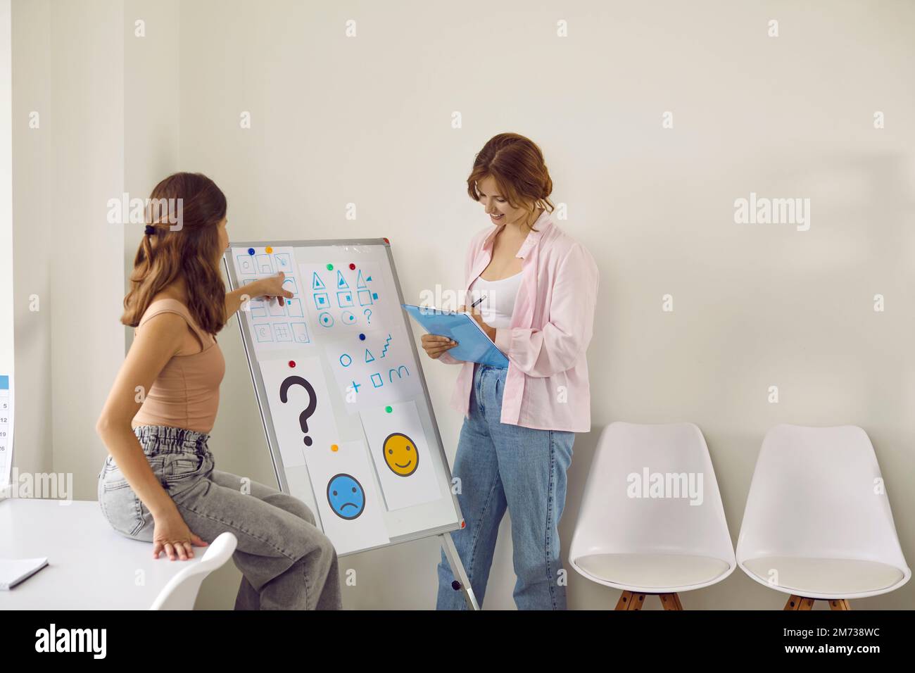 Friendly female psychologist talks to teenage girl and conducts psychological tests. Stock Photo