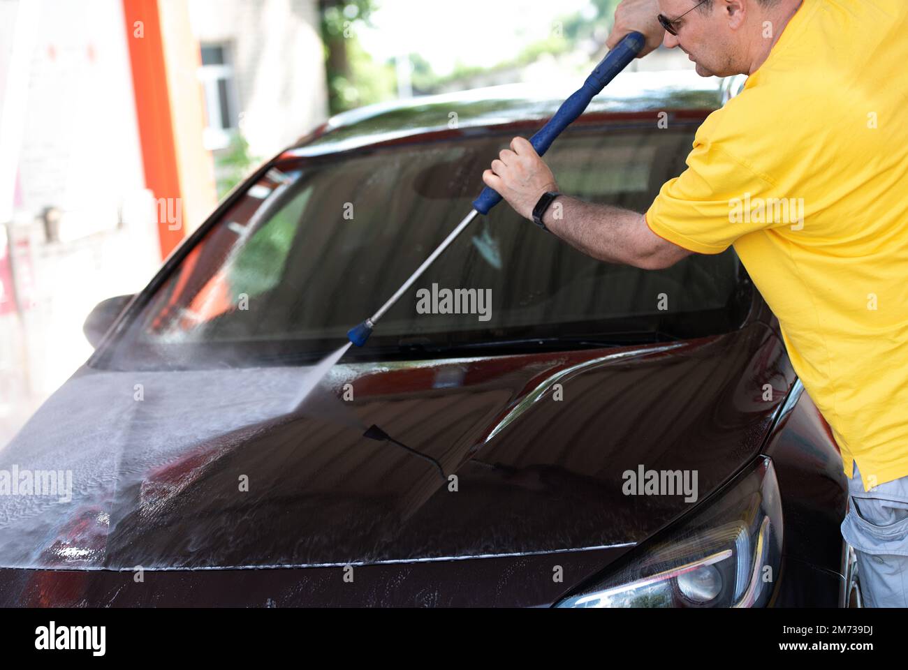 Car washing. Mature caucasian man cleaning automobile using high pressure jet water. Stock Photo