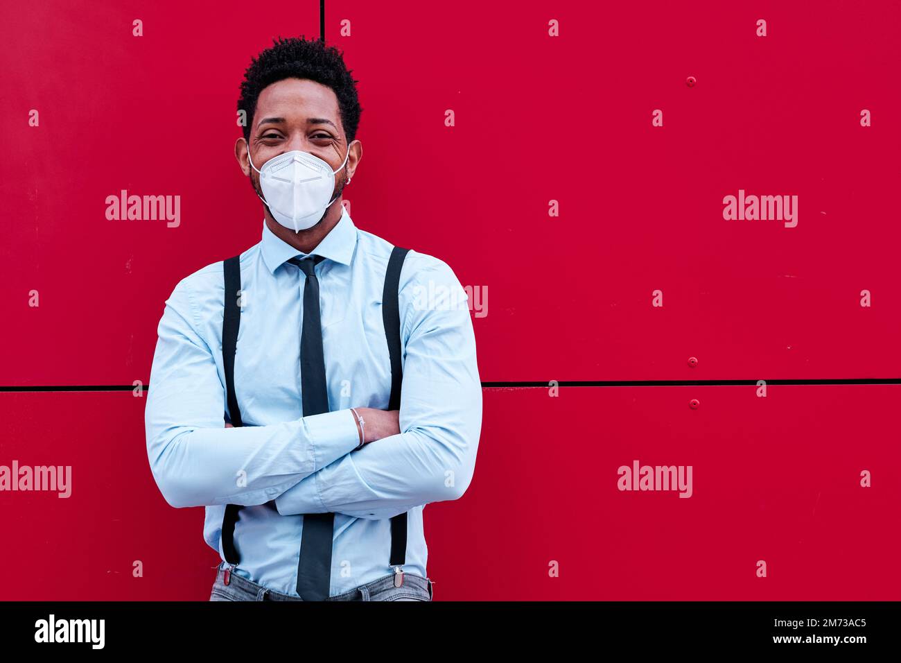 Businessman with face mask standing with his arms crossed outdoors. Stock Photo