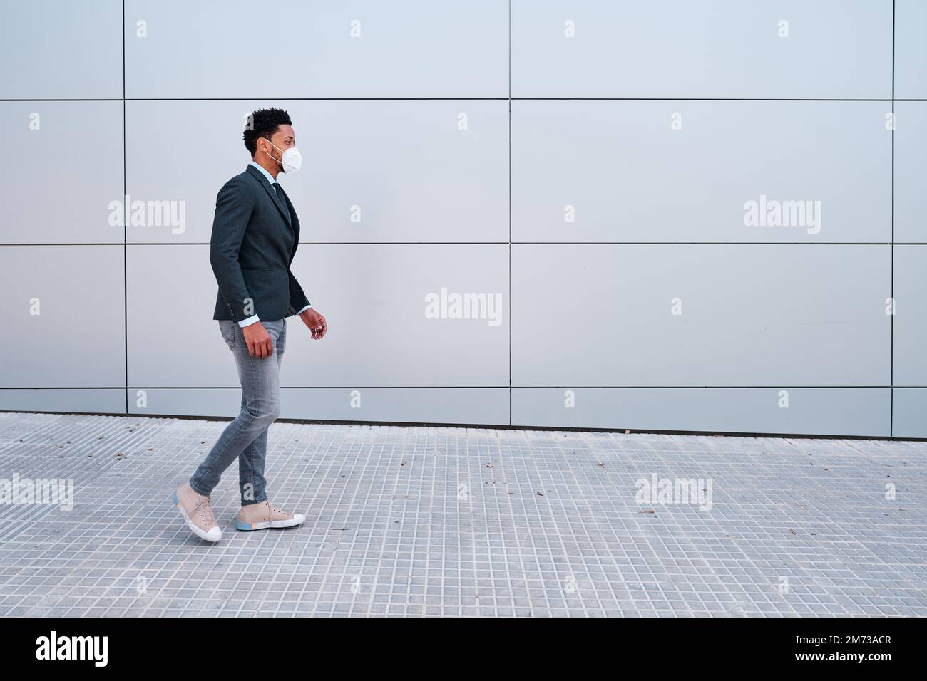 Businessman with face mask walking outdoors on the street in financial district. Stock Photo