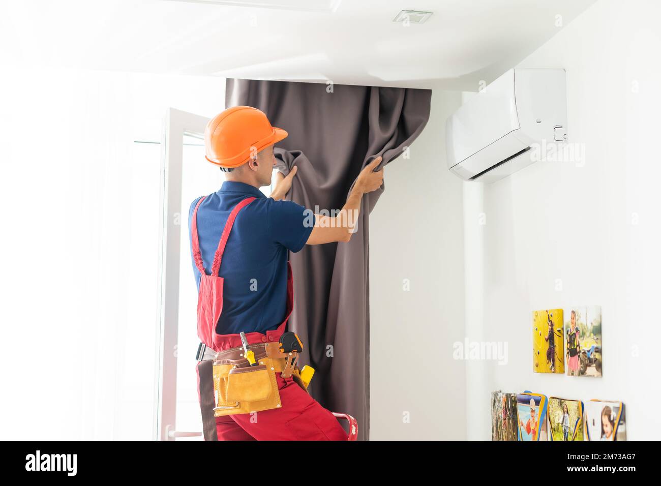 man doing house works, attach the railing and hang curtains at home. Stock Photo