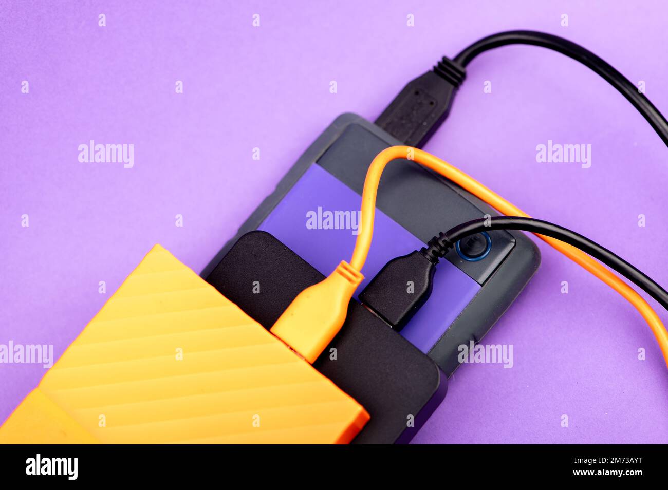 Multicolored external portable hard disk drives isolated on violet background Stock Photo