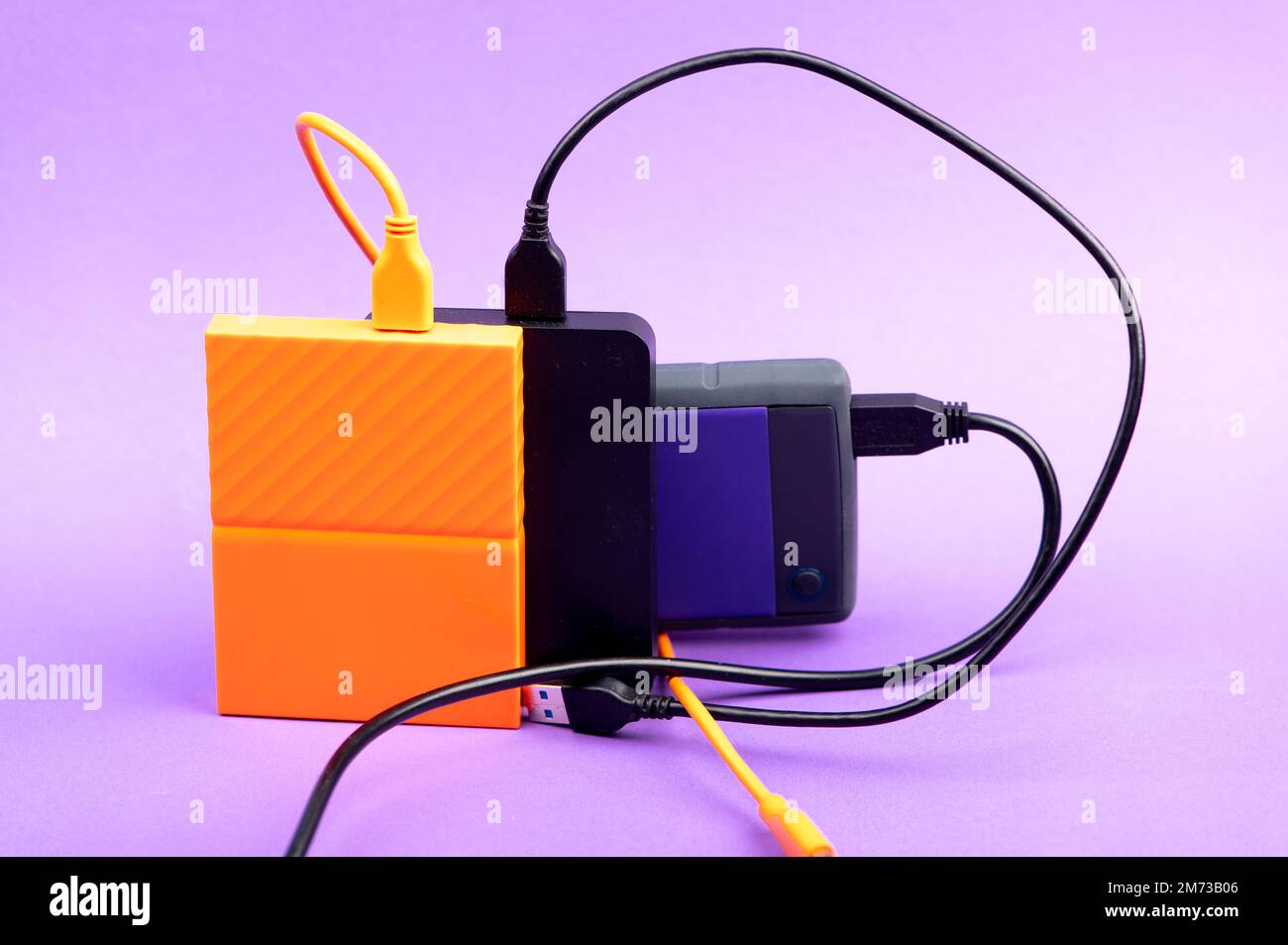 Multicolored external portable hard disk drives isolated on violet background Stock Photo