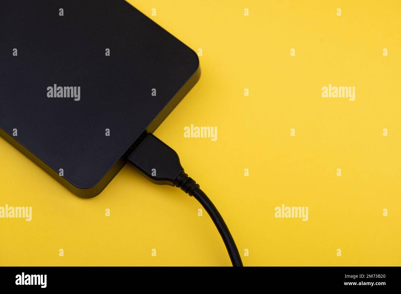 Black external portable hard disk drives isolated on yellow background
