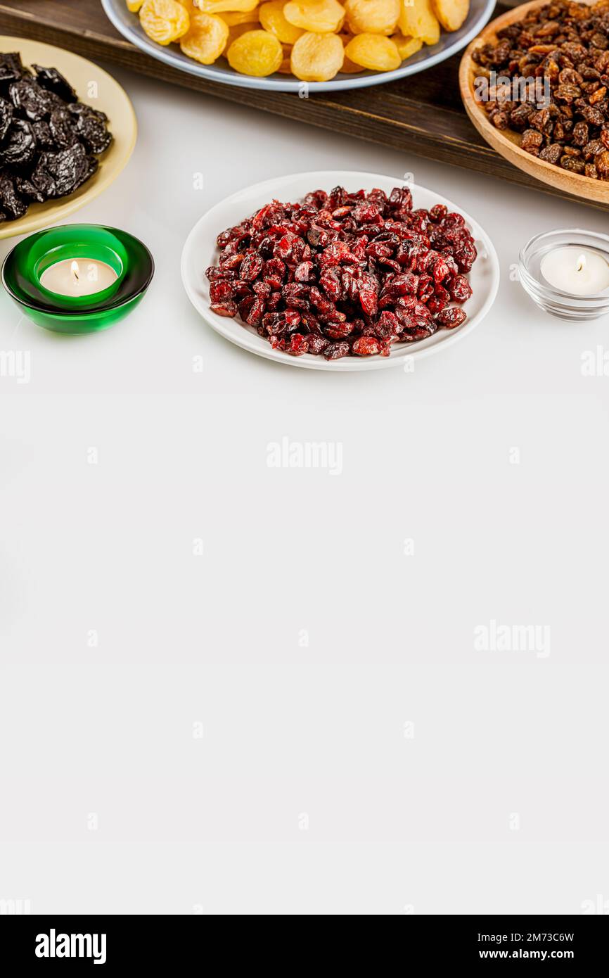 Ramadan food vertical banner with dried apricots, cranberries, raisins, and prunes on plates on white background with copy space. Dry fruits assortmen Stock Photo
