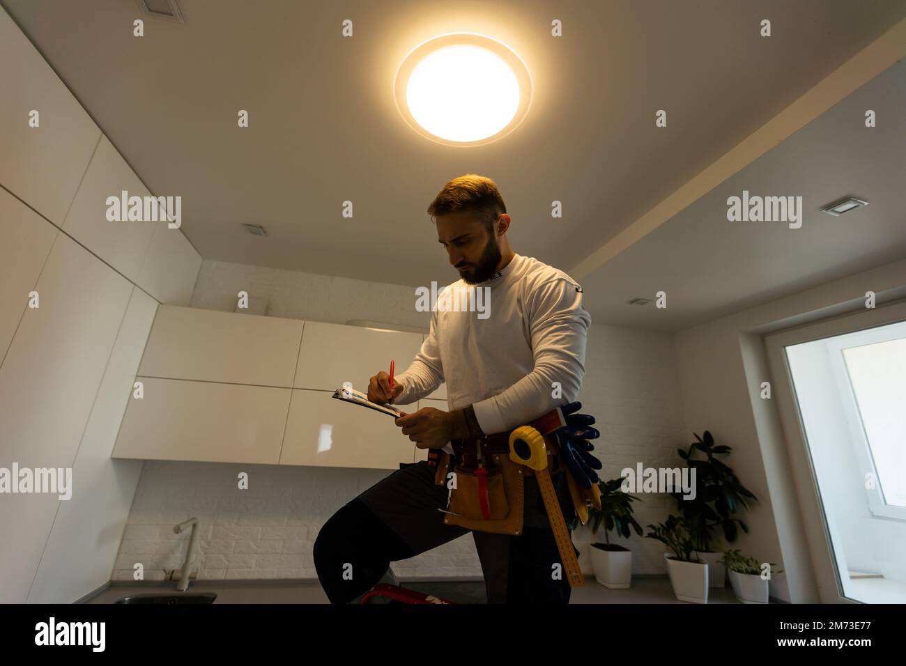 Installation lighting. Builder is holding a tablet in his hands. Concept - lighting engineer. Process installing. Electrician Stock Photo