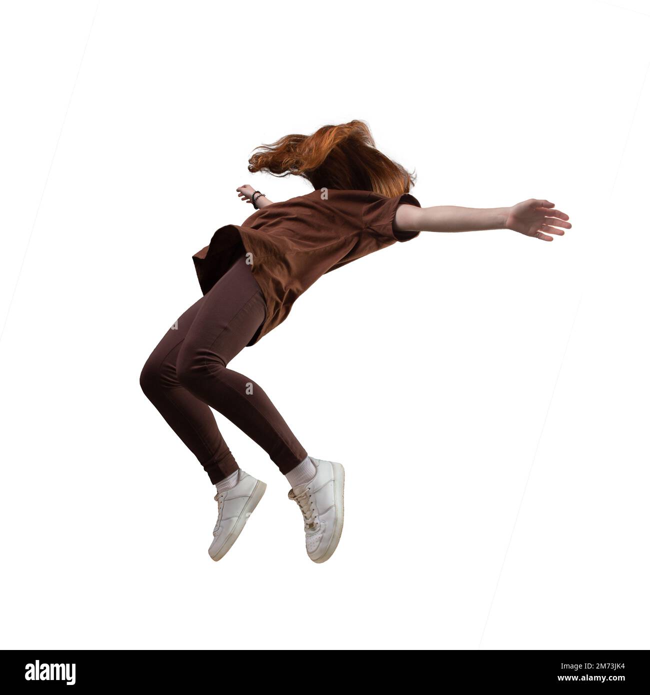 Side view of teen age girl in zero gravity or a fall. Ggirl is flying, Falling or floating in the air. Girl weared in brown trousers and t-shirt. Isol Stock Photo