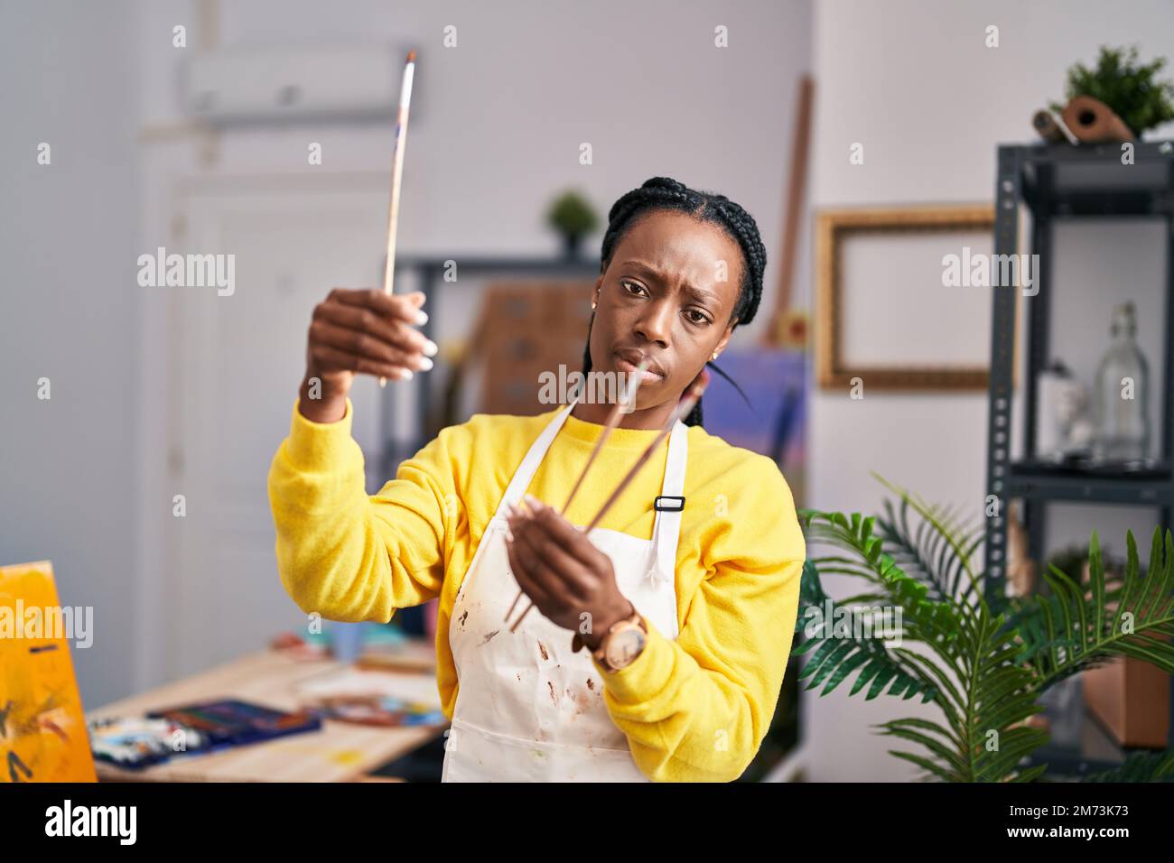 African american woman artist holding paintbrushes at art studio Stock ...