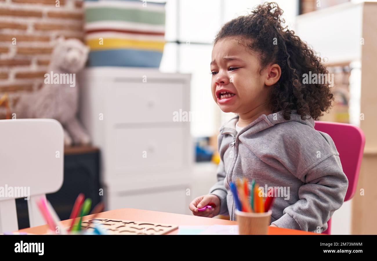 African american toddler sitting on table crying at kindergarten Stock ...