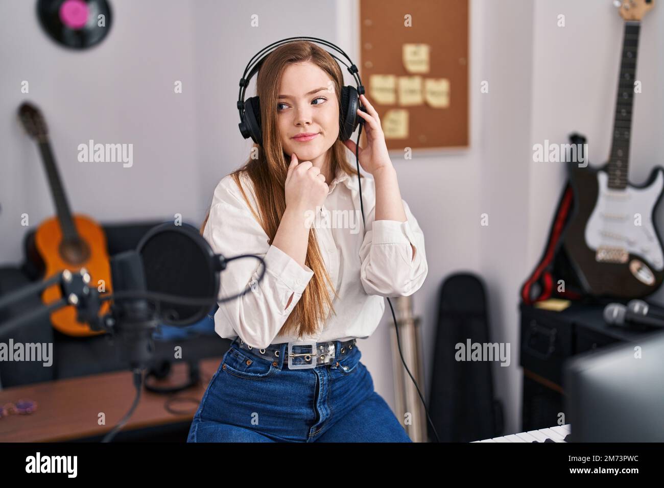Confusing Music Young caucasian woman recording song at music studio serious face ...