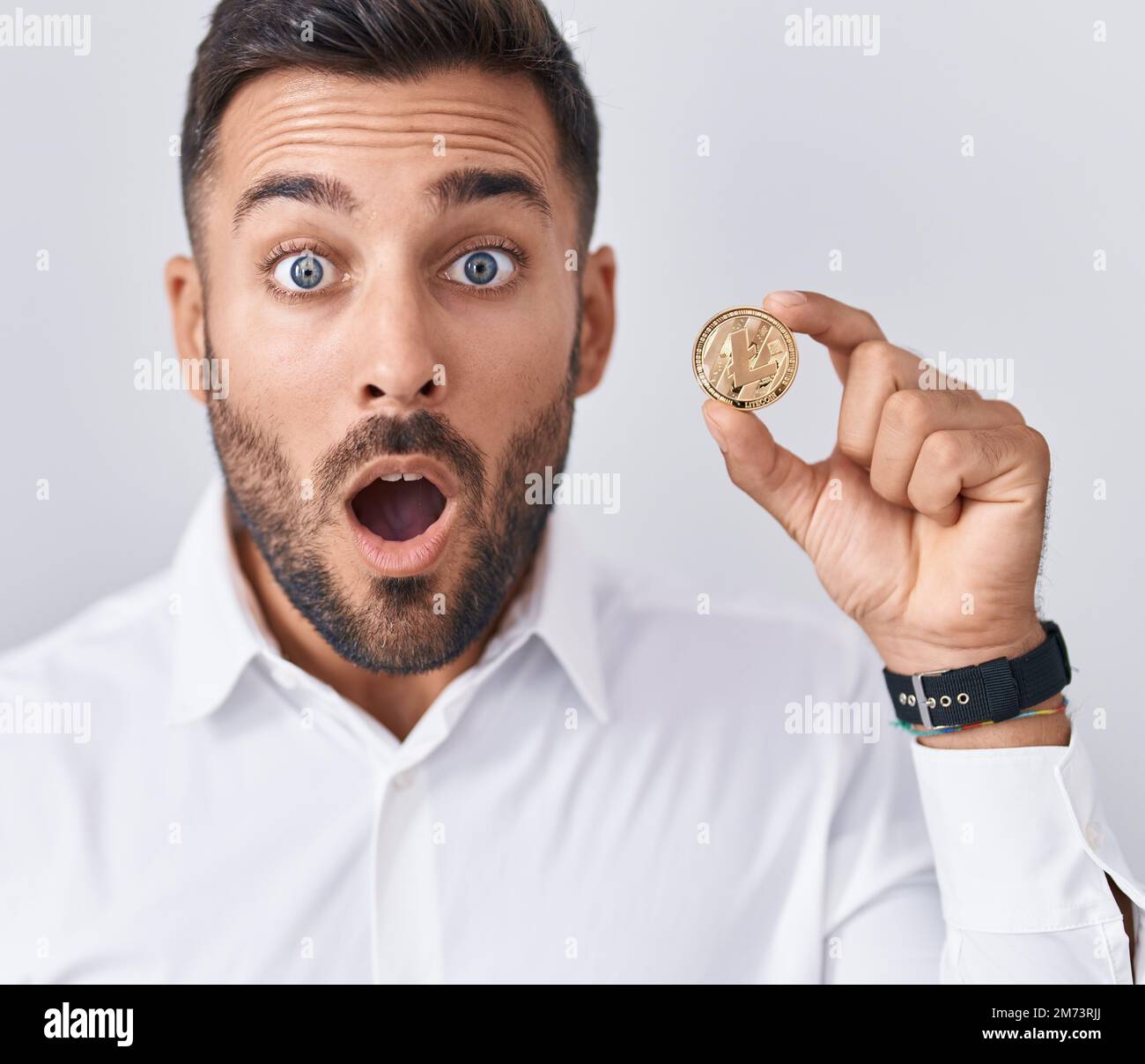 Coiny Scared Handsome hispanic man holding litecoin cryptocurrency coin scared and ...