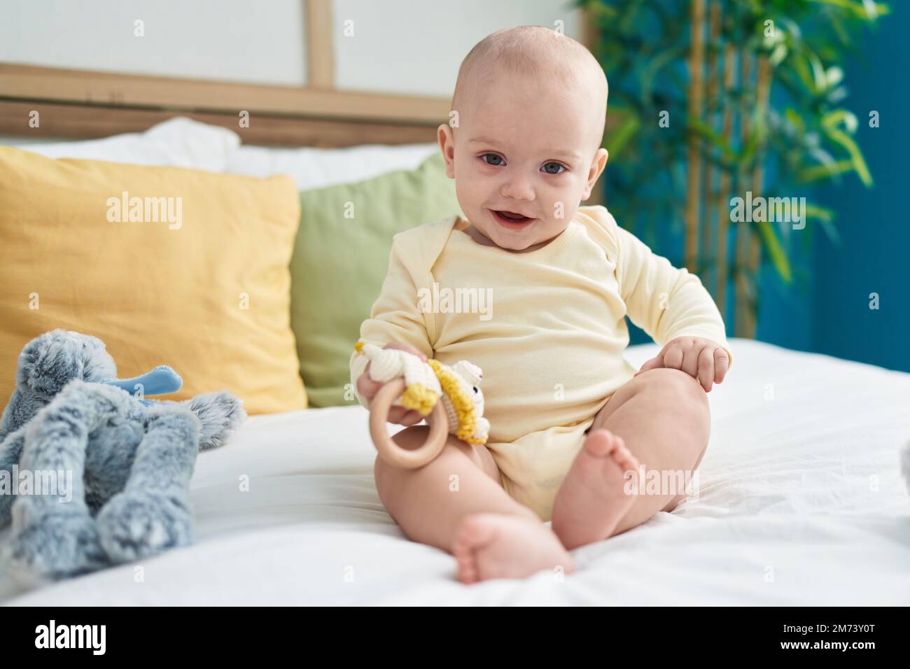 Adorable caucasian baby holding toy sitting on bed at bedroom Stock ...