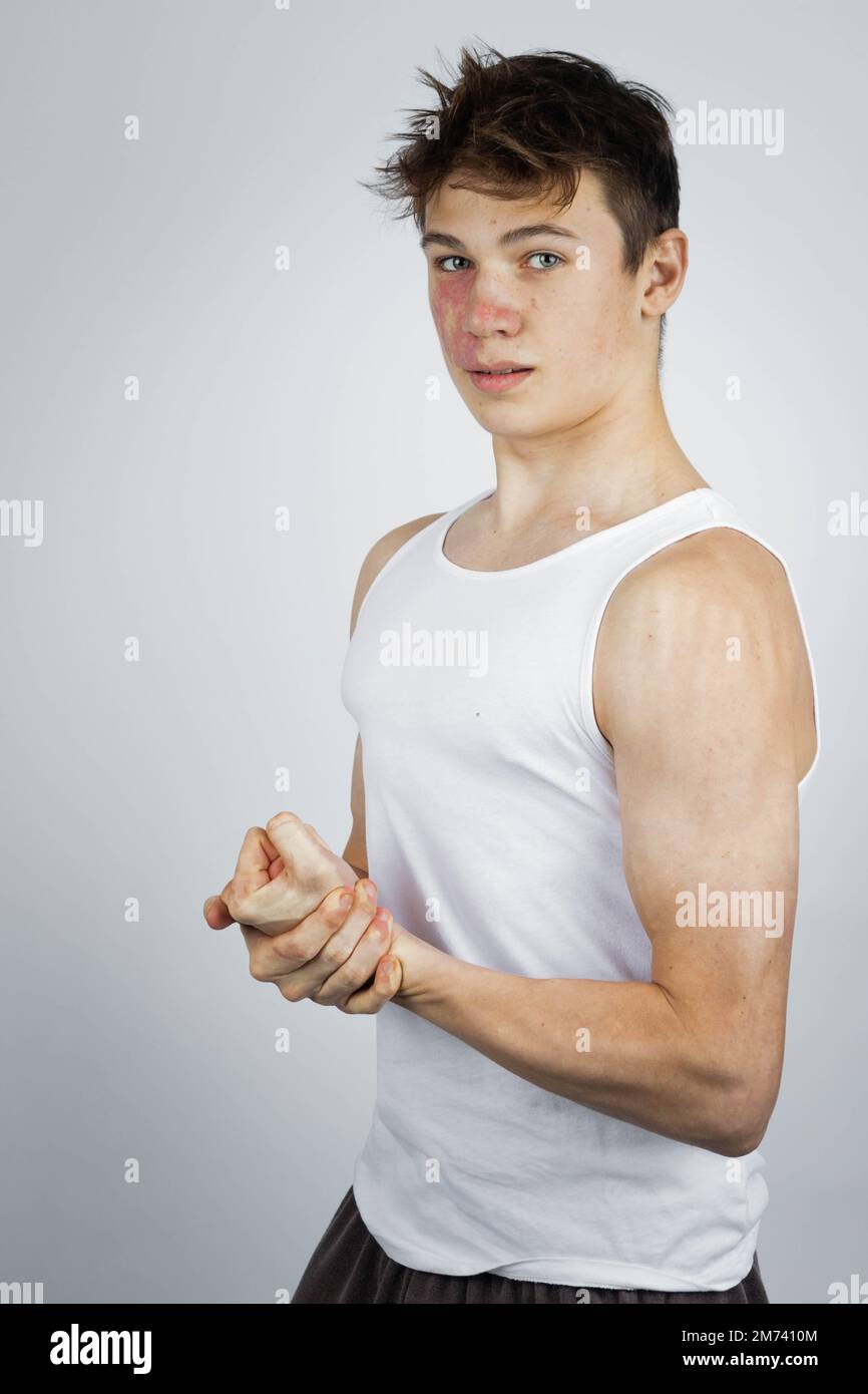 A 17 year old teenage boy wearing a white tank top flexing his arm ...