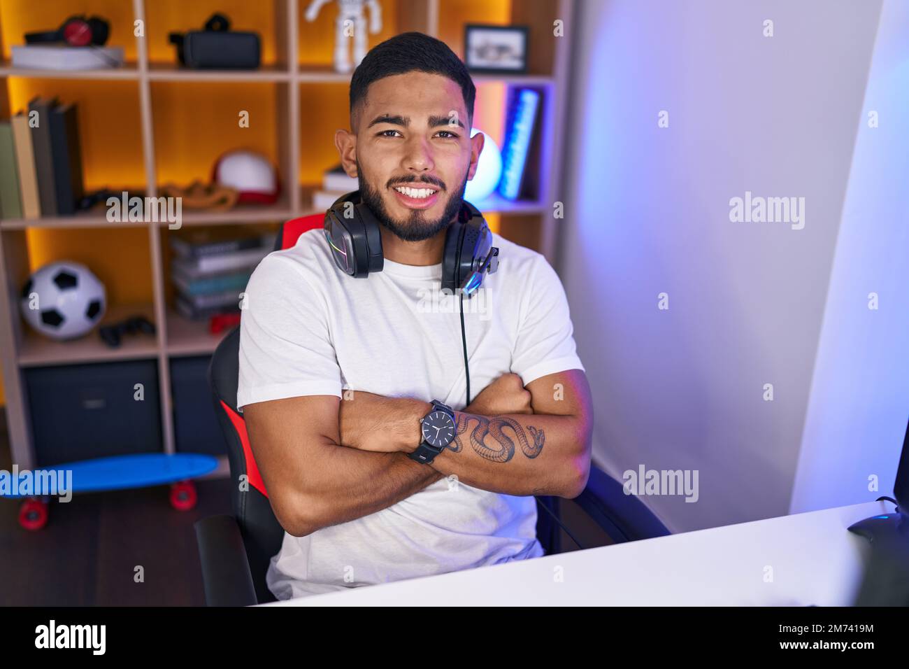 Young latin man streamer smiling confident sitting with arms crossed ...