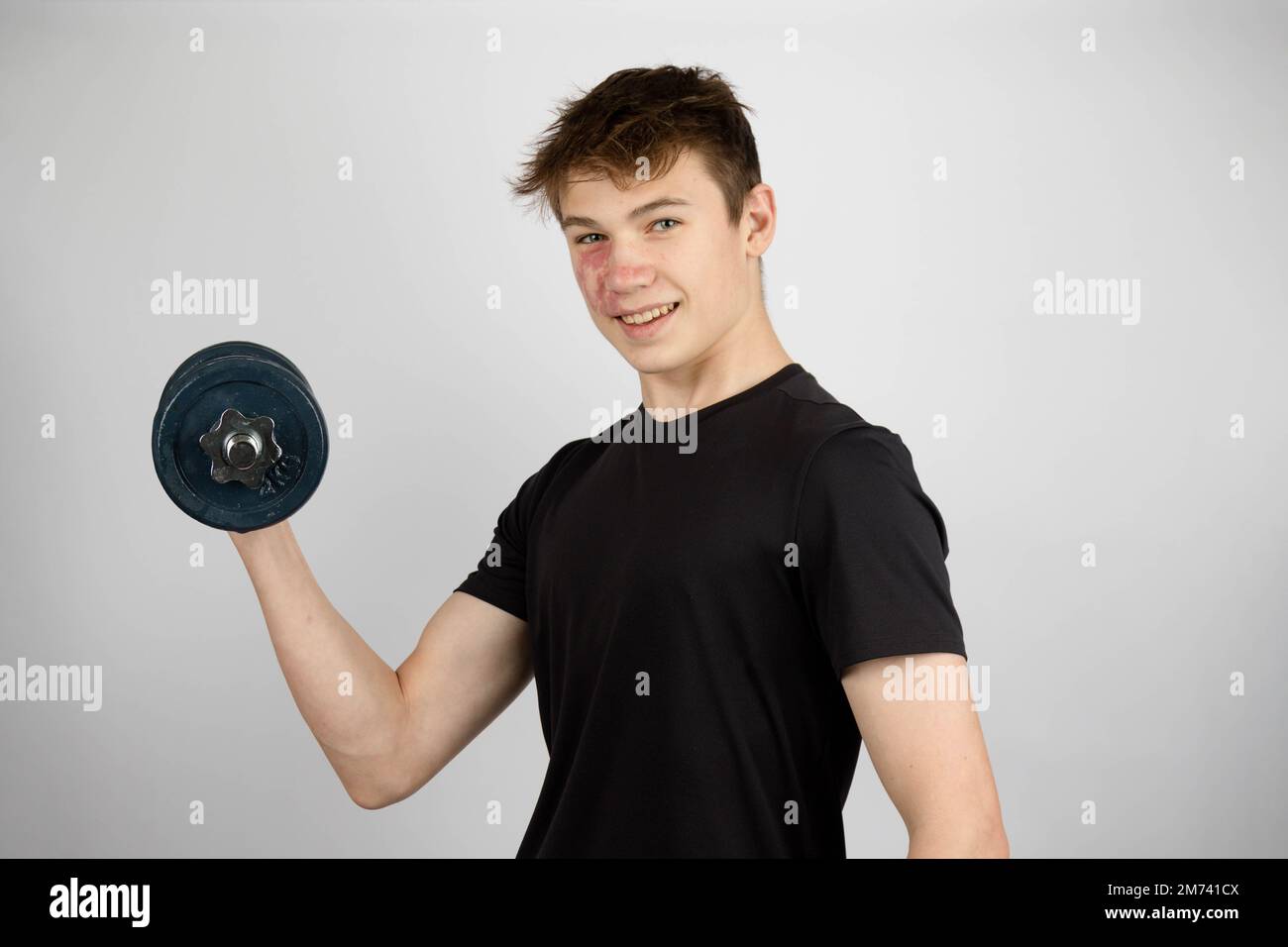 A Portrait of a 17 year old boy wearing a black tshirt using a dumbell Stock Photo Alamy