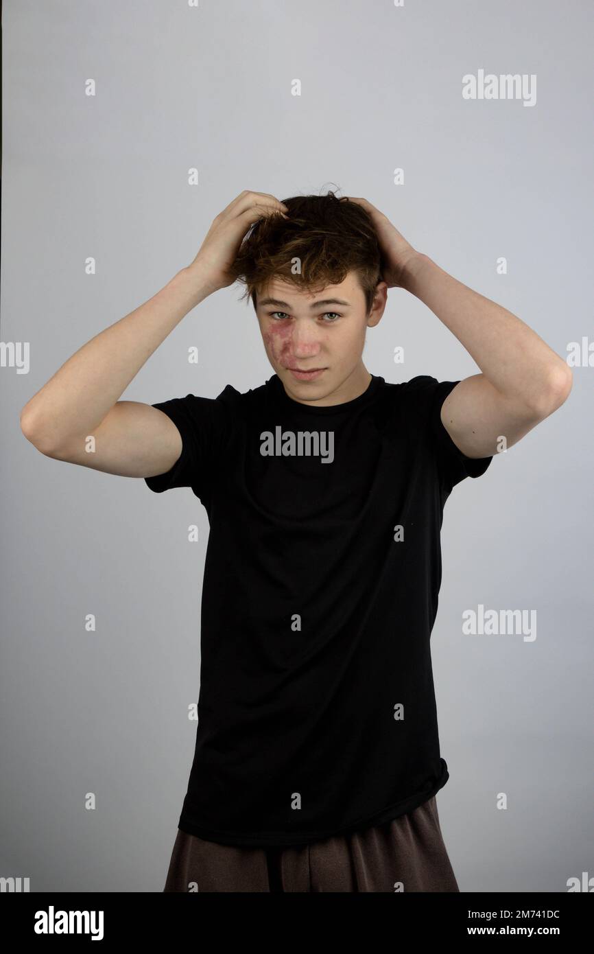 A Portrait of a 17 year old boy wearing a black tshirt playing with his hair Stock Photo Alamy