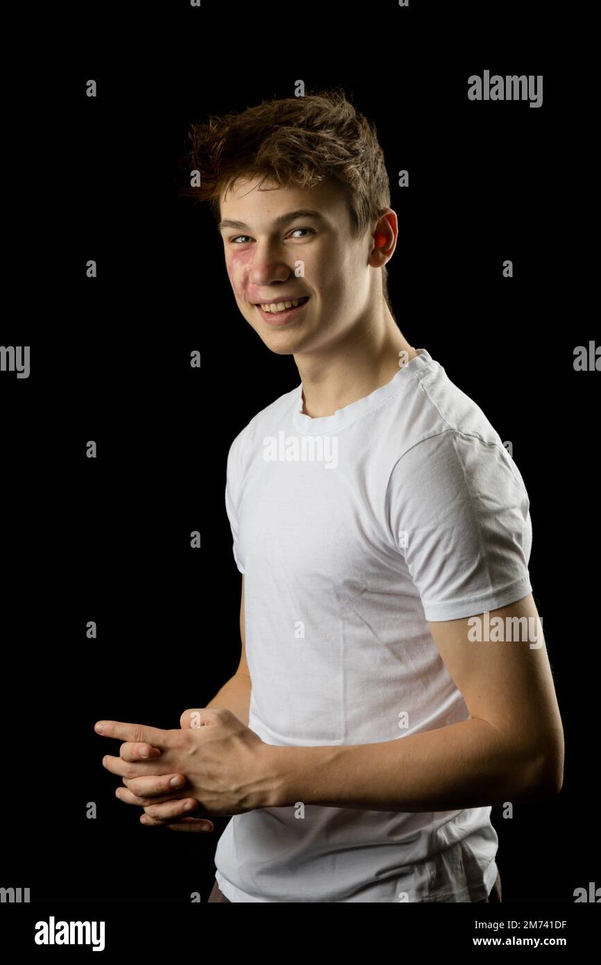 Portrait of a happy 17 year old boy against a black background Stock
