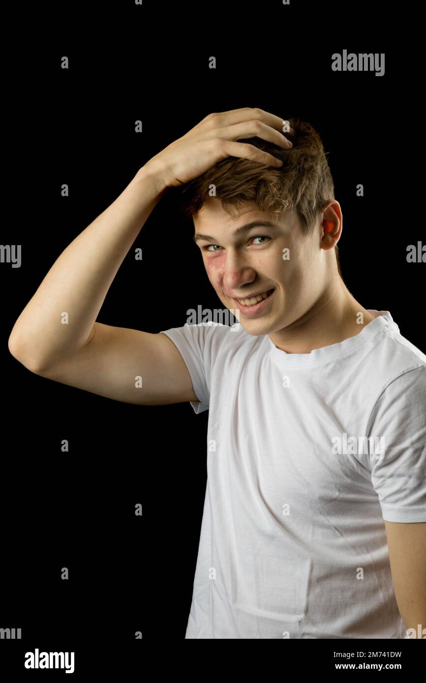 Headshot of a 17 year old boy wearing a white tshirt against a black background playing with