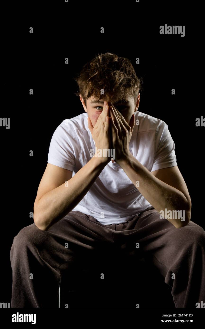 Portrait of a sitting emotional looking 17 year old teenage boy Stock