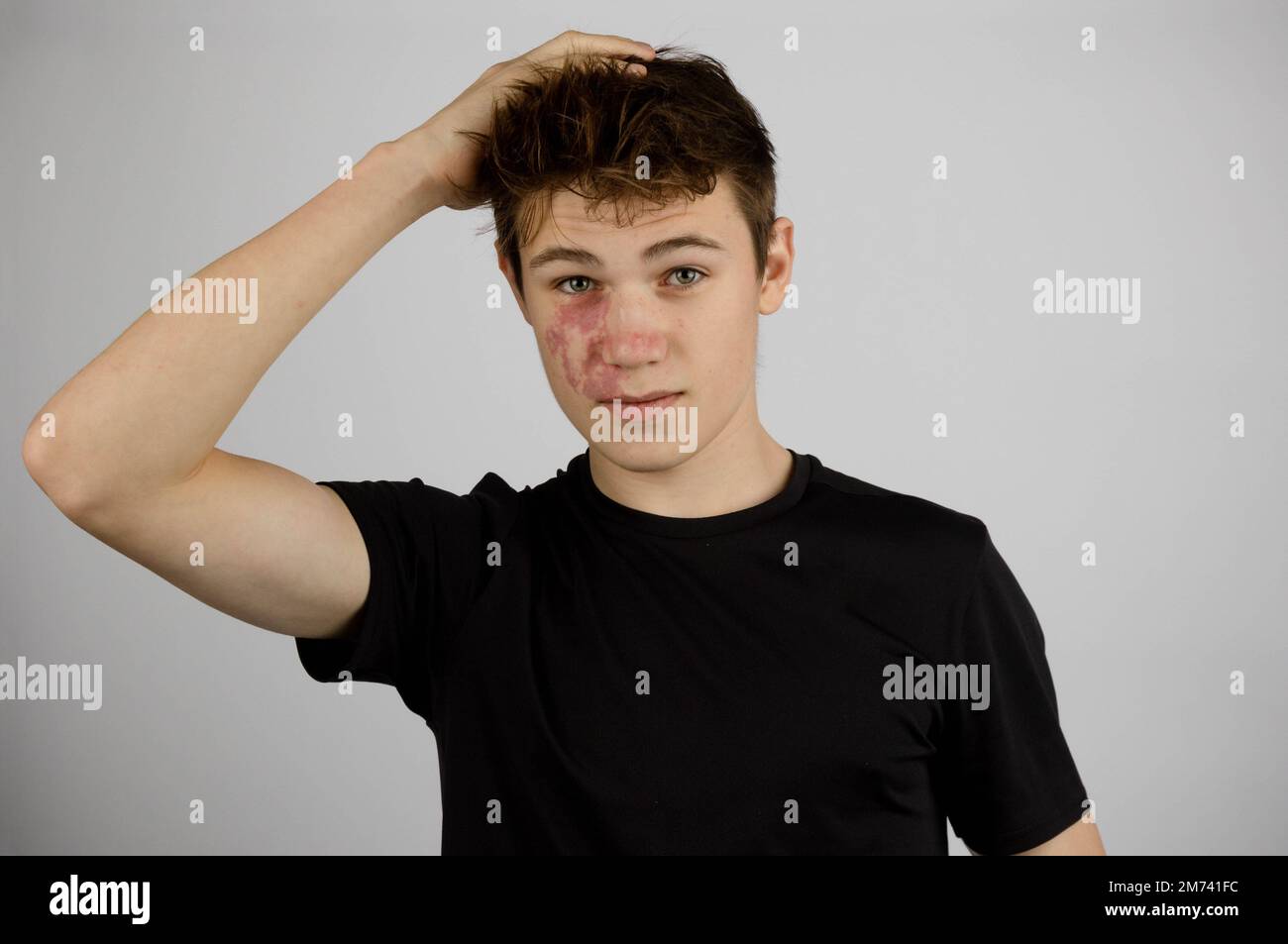 A Portrait of a 17 year old boy wearing a black tshirt playing with his hair Stock Photo Alamy