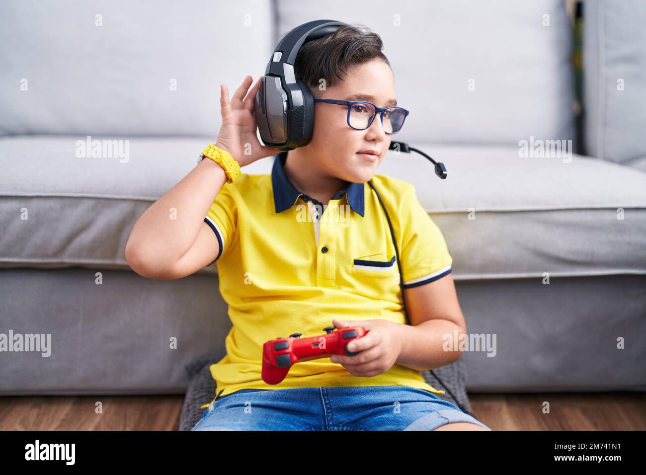 Kid Using Controller Young hispanic kid playing video game holding controller wearing ...