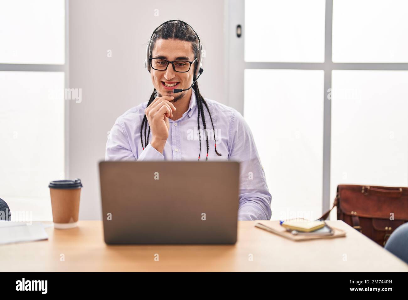 Hispanic Man Using Computer Hispanic man with long hair working using computer laptop smiling ...