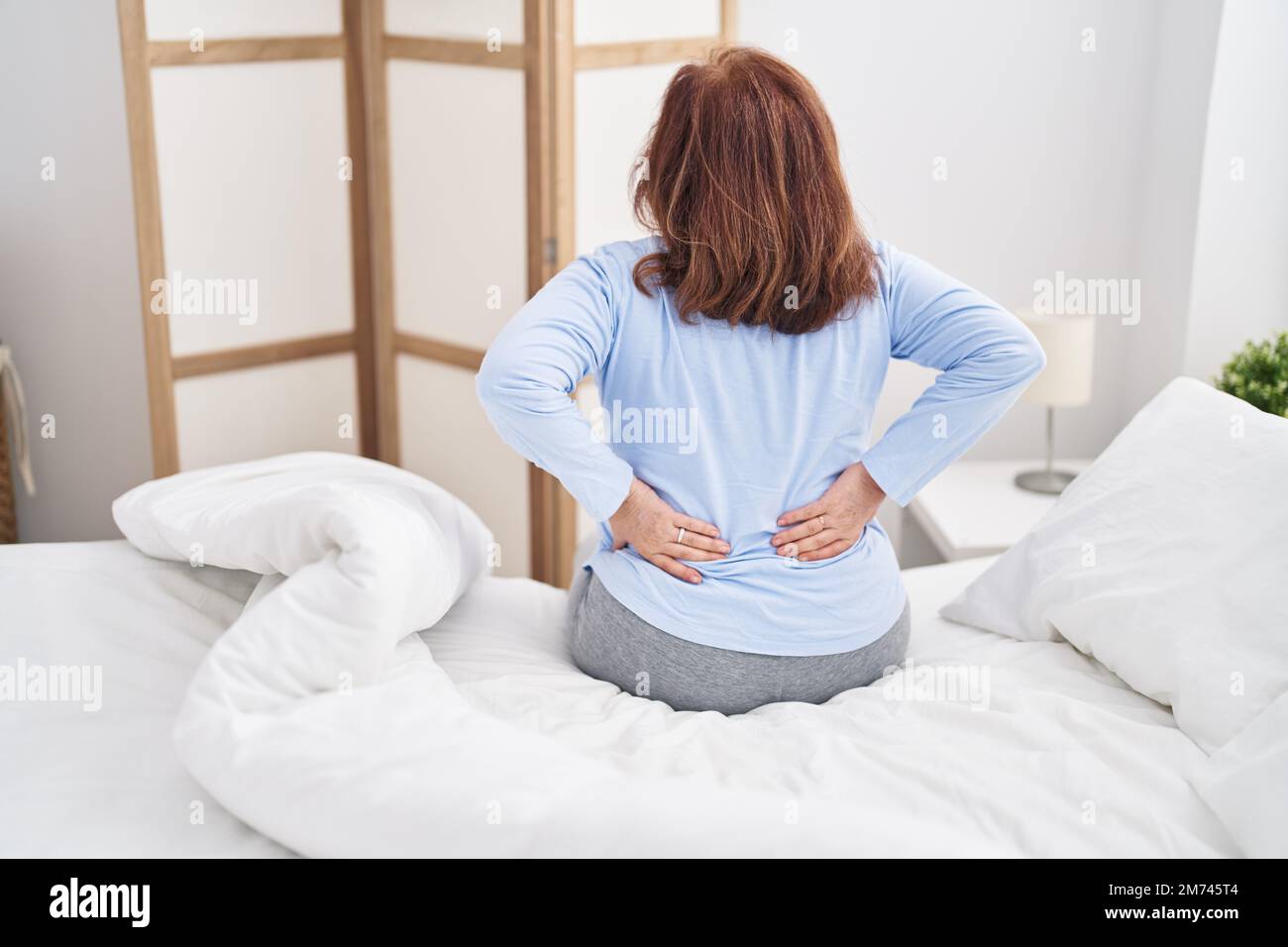 Senior woman suffering for backache sitting on bed at bedroom Stock