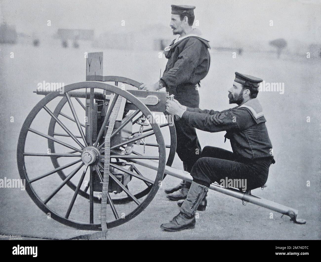 “Maxim Gun Practice at Whale Island, Portsmouth”. Circa.1895. Two Royal Navy seamen of HMS Excellent, the Portsmouth gunnery ship, are practising with a Maxim gun, the latest type of machine gun adopted by the Navy. The special feature of the Maxim (so named after its inventor) is its automatic action. The firer presses a button and the gun goes on firing by itself until its ammunition, carried on a belt of from 150 to 200 cartridges, stops. The belts are quickly replaced, and 600 shots a minute, in a continuous stream of bullets, can be fired. Stock Photo