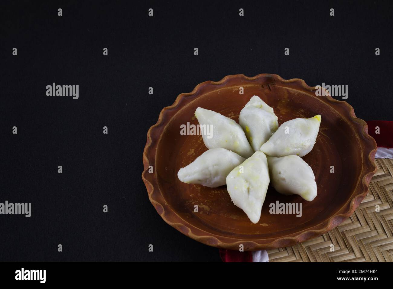 makar sangkranti or poush sangkranti celebration with puli pithe or bengali rice flour dumplings with coconut fillings served on a clay plate with jag Stock Photo