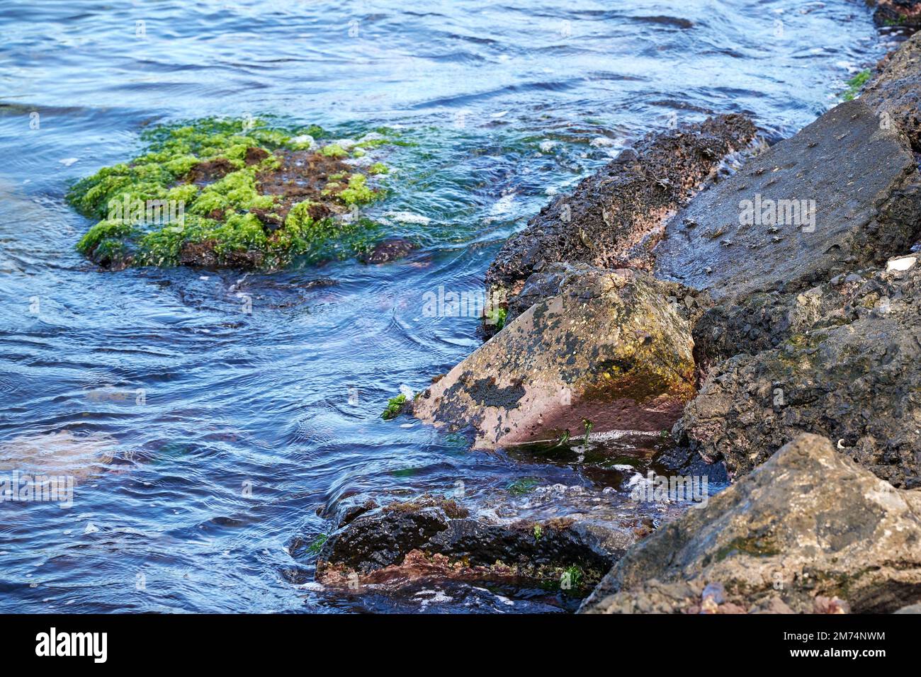 A high angle shot of blue sea waves splashing on a rocky shore Stock ...