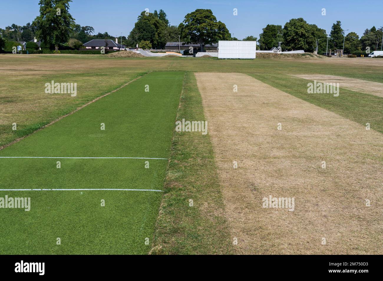 Drought hardened cricket pitch in August in Scotland with year-round artificial turf pitch alongside it Stock Photo