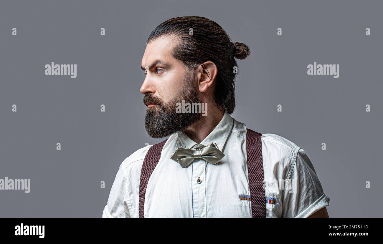 Beard man in bow tie and suspenders. Male in shirt correcting his colorful tie. Portrait of handsome bearded man in white shirt and bow tie, suspender Stock Photo