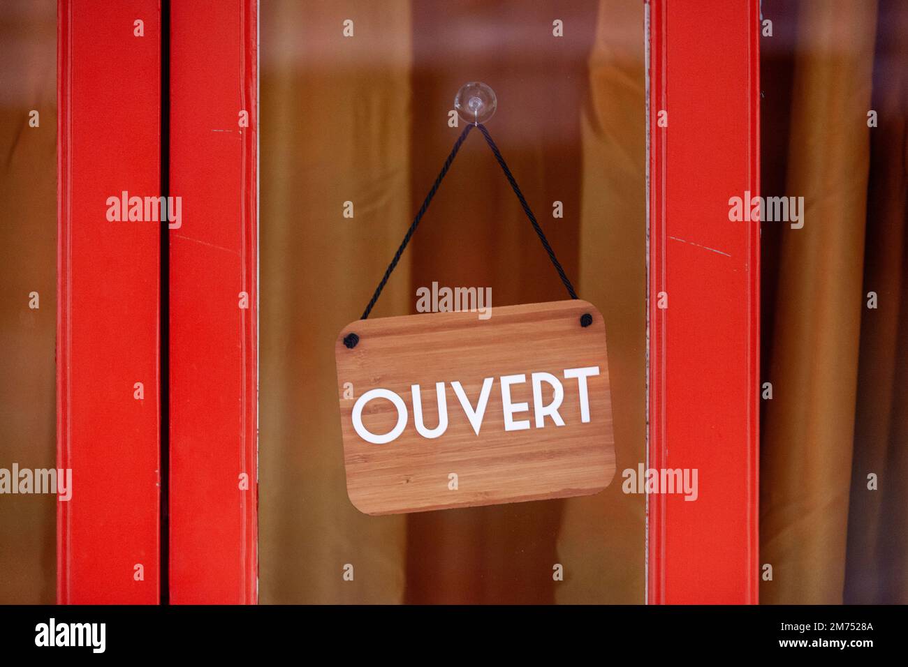Sign at the entrance of a restaurant saying in French - Ouvert - meaning in English - Open -. Stock Photo