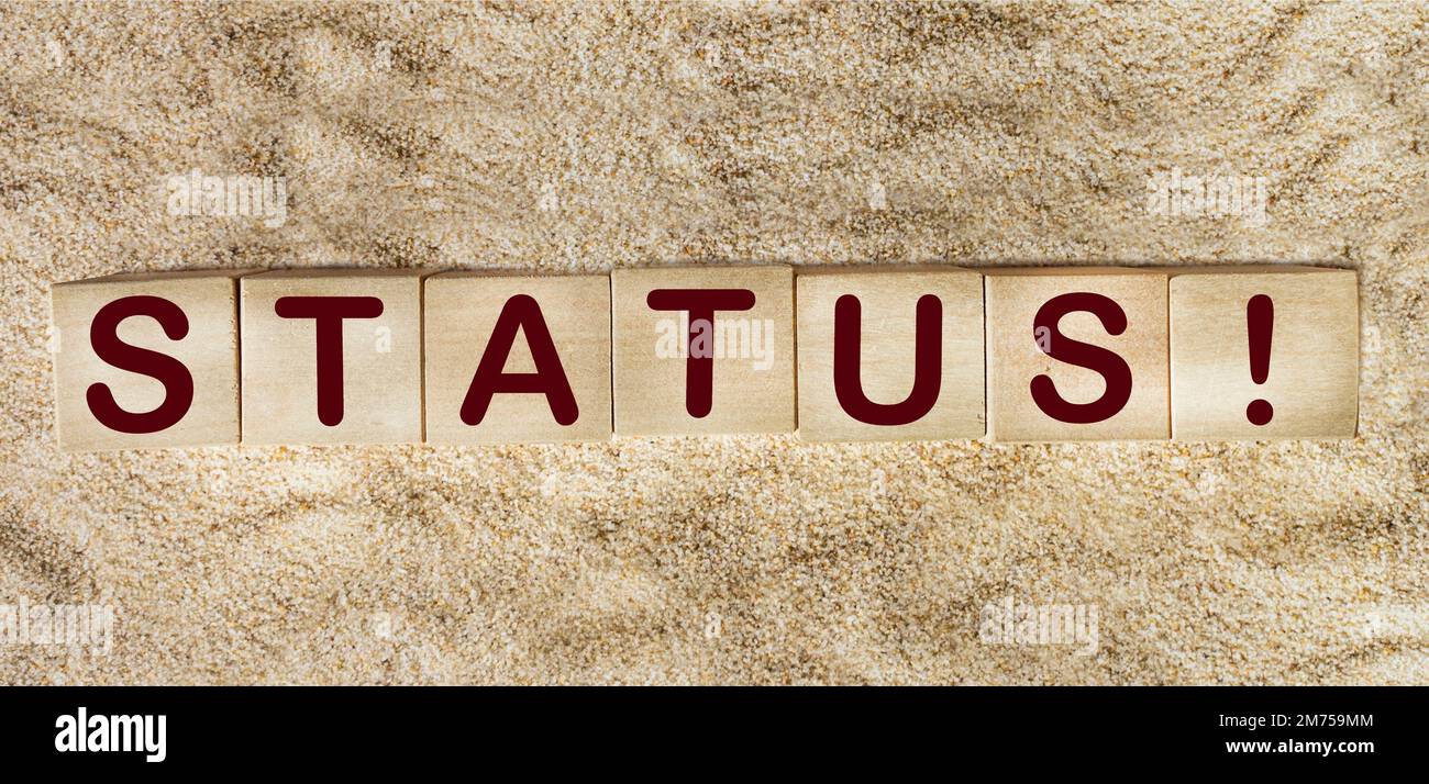 The word STATUS. Wooden cubes with letters on a sand background Stock