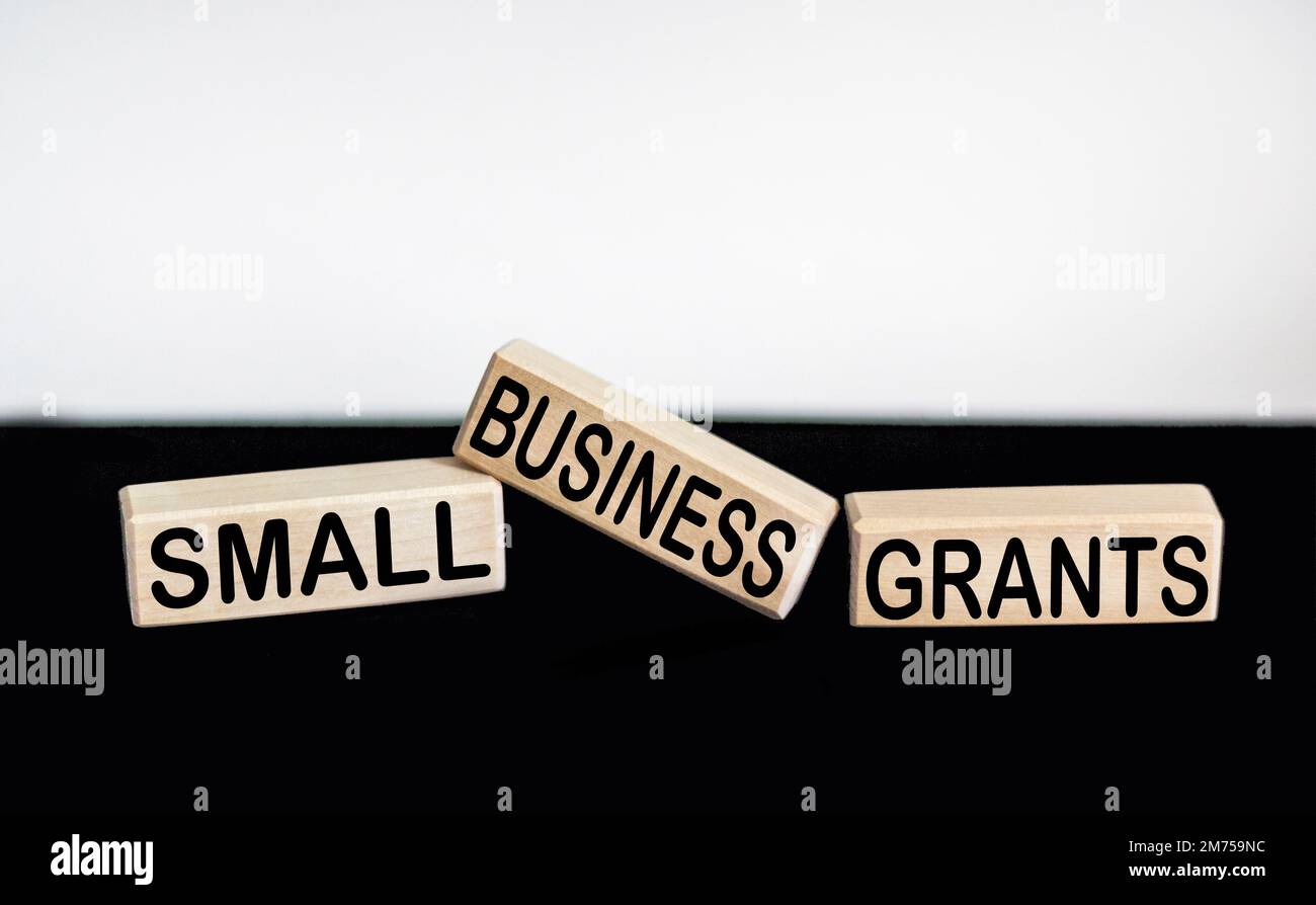Small business grant symbol. Conceptual words Small Business Grant on wooden blocks on a black and white background. The concept of grants for busines Stock Photo