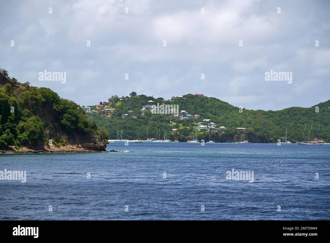 A landscape view of the sea with houses in the green hills on the beach ...