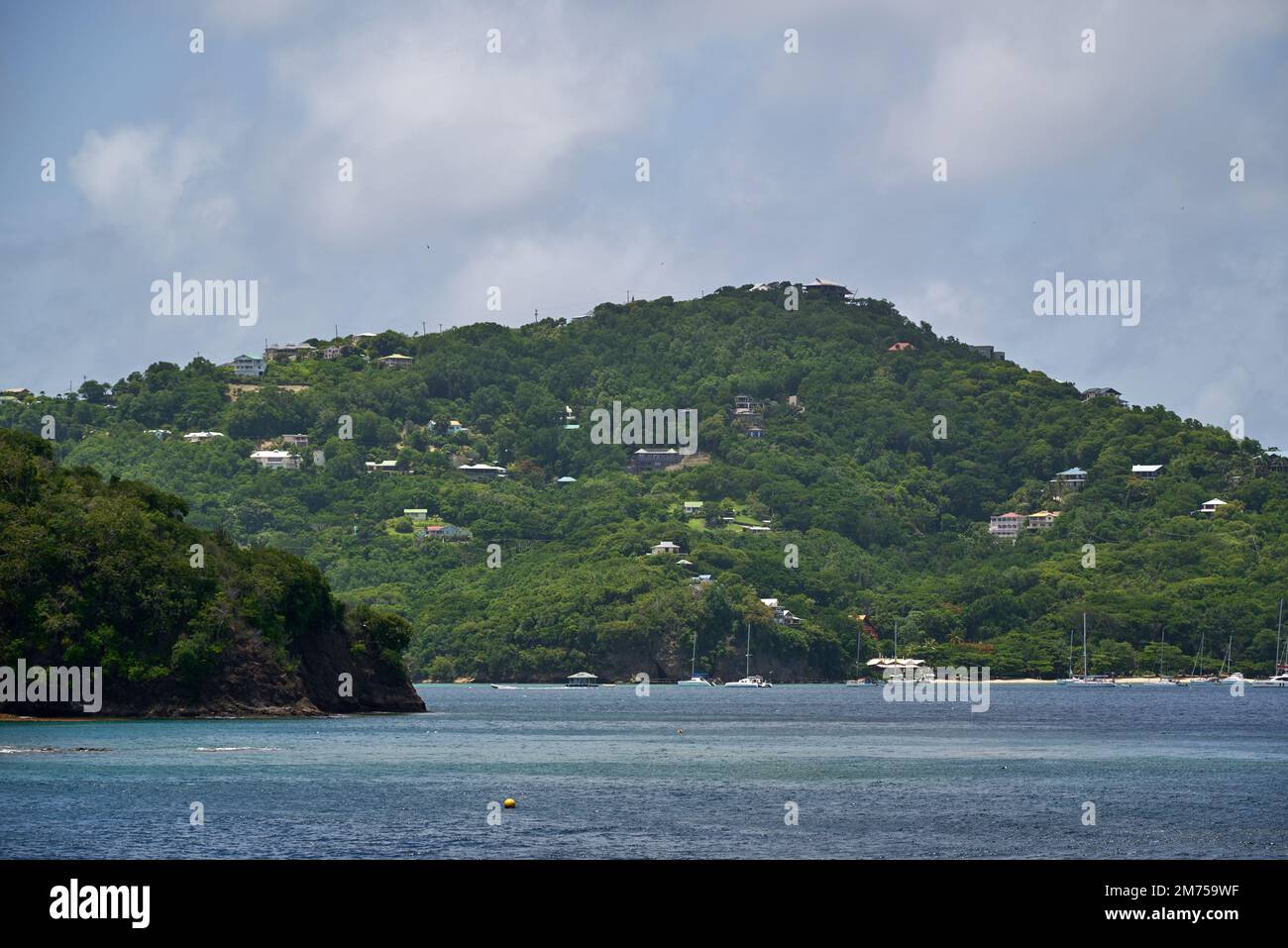 A landscape view of the sea with houses in the green hills on the beach ...