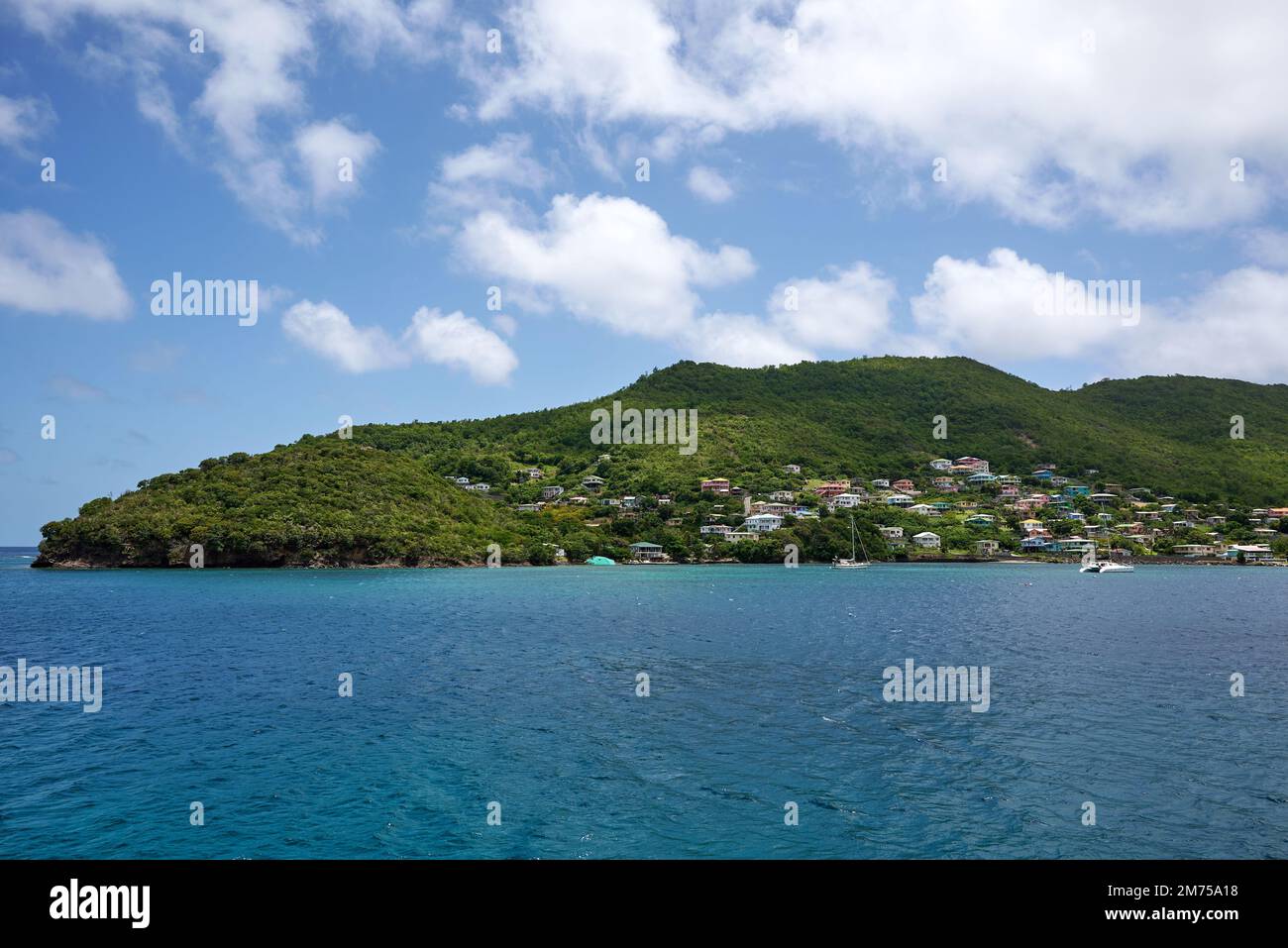 A landscape view of the sea with houses in the green hills on the beach ...