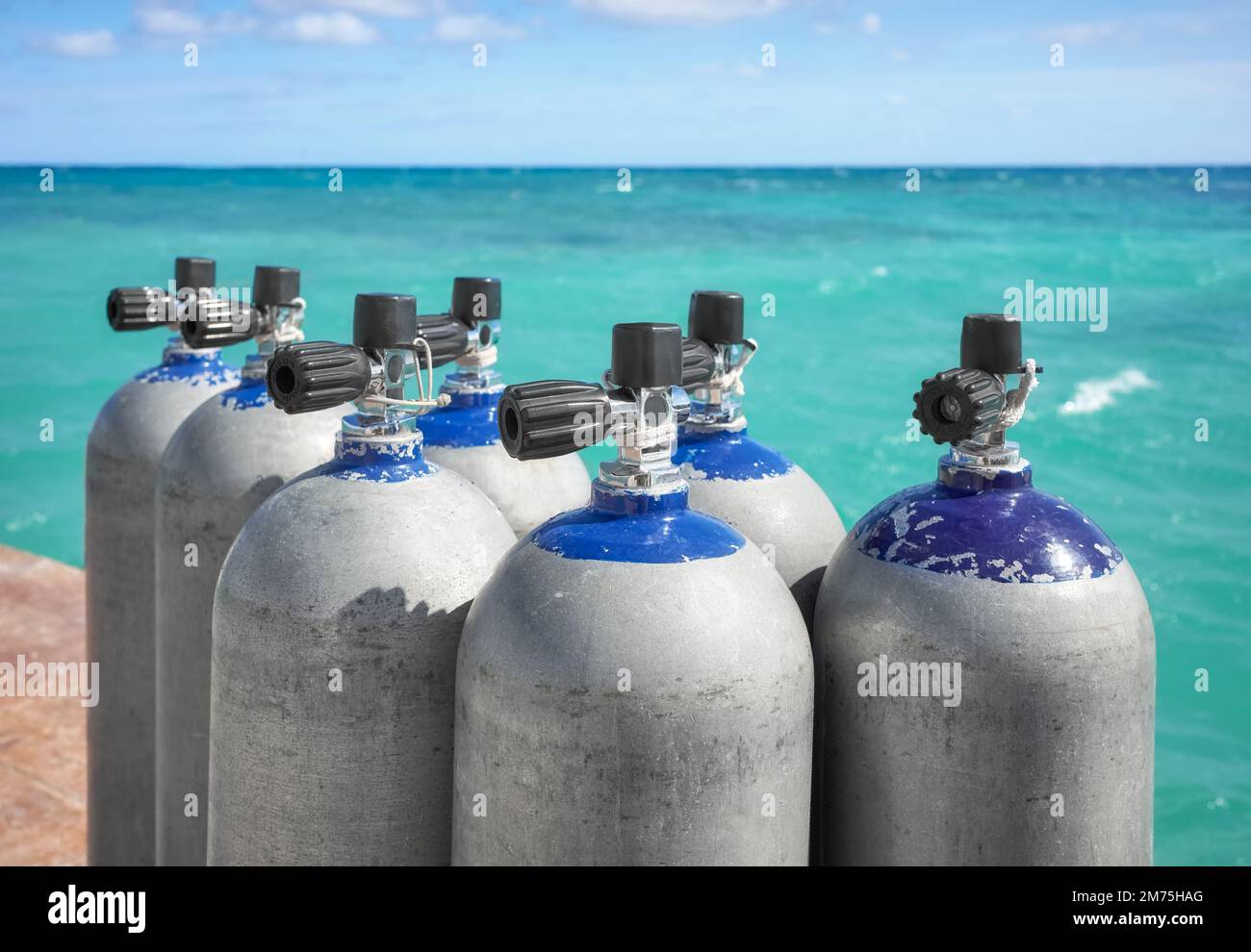 Close up picture of scuba tanks with turquoise water in the background, selective focus. Stock Photo