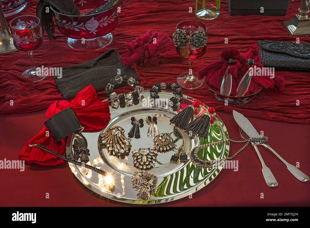 Rhinestone jewellery and accessories decorated on a silver plate and red cloth, Bavaria, Germany Stock Photo