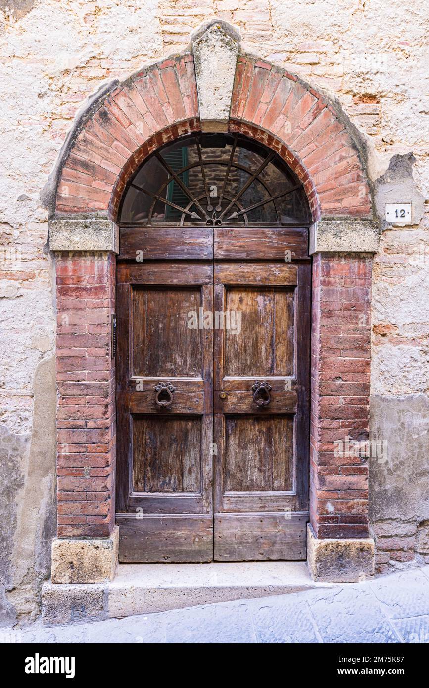 Weathered old round arch front door, Motepulciano, Tuscany, Italy Stock Photo