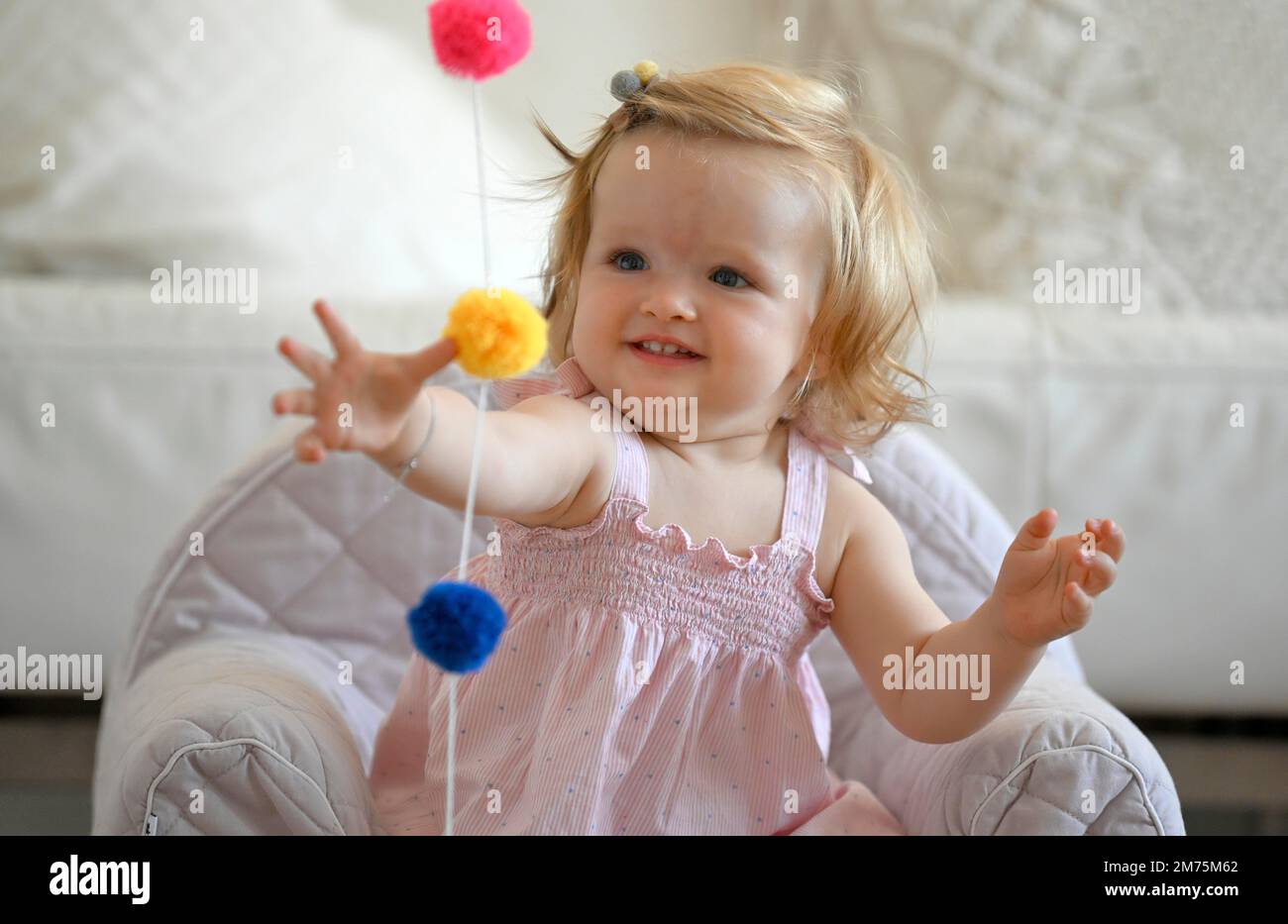 Girl, toddler, 11 months, plays with coloured wool balls, laughs, Baden
