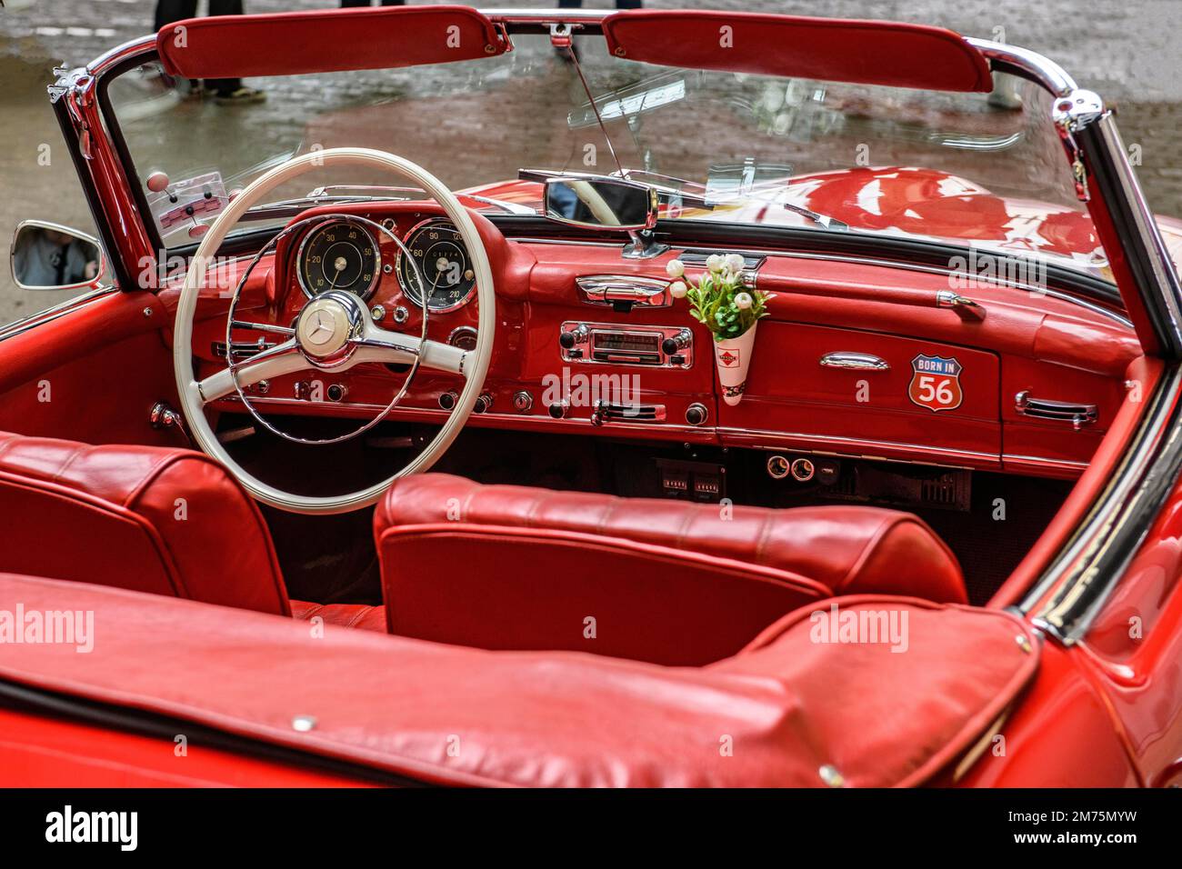 View into interior of convertible classic car Mercedes SL 190 with red leather, white spoke steering wheel, dashboard with flower vase, Duesseldorf Stock Photo