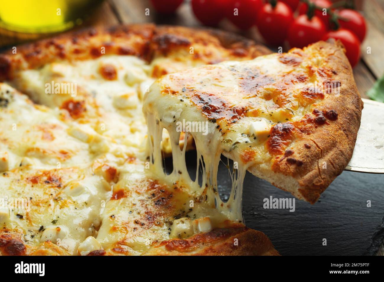 A slice of hot Italian pizza with stretching cheese. Pizza four cheeses with basil. Stock Photo