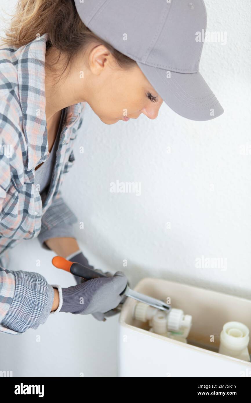 female plumber repairing toilet flush Stock Photo