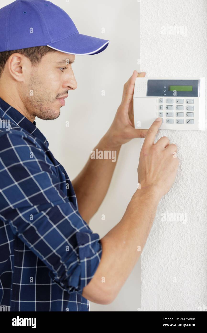 male technician installing alarm system indoors Stock Photo