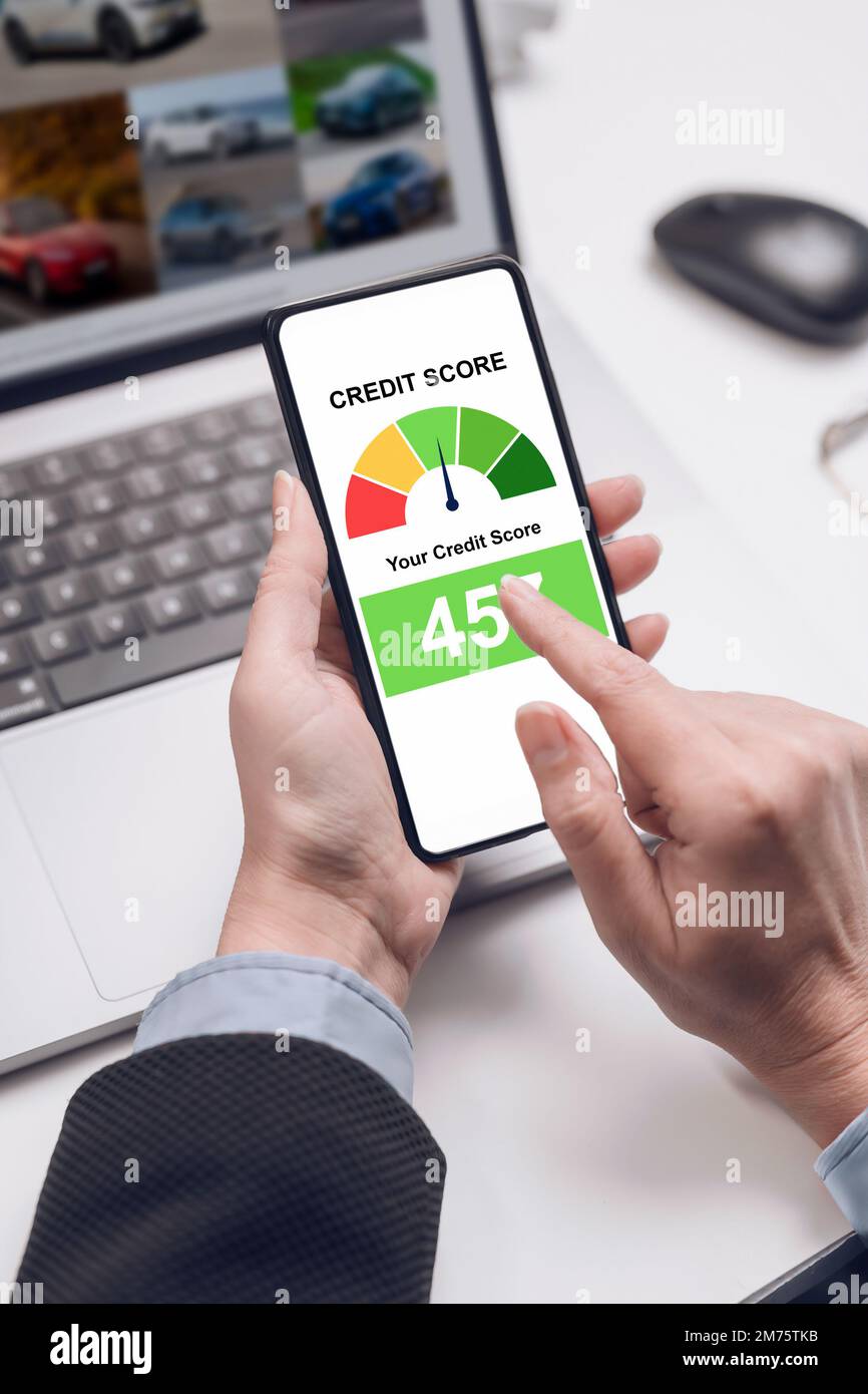A woman holding a smartphone shows a credit score app on the screen. bank credit report. Stock Photo